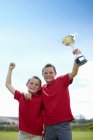 Boys cheering with trophy outdoors, focus on foreground — Stock Photo