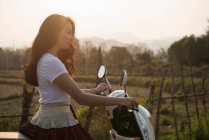 Woman on moped in rural scene — Stock Photo