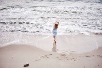 Frau mit Hut spaziert am Strand — Stockfoto