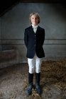 Мальчик, стоящий в одежде лошади в конюшне — стоковое фото