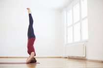 Donna in studio di esercizio facendo headstand — Foto stock
