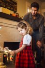 Niña con padre colocando chucherías en el árbol de Navidad - foto de stock