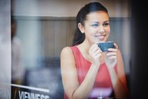 Giovane donna seduta in un caffè con bevanda calda — Foto stock