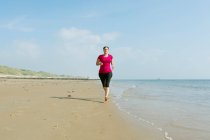 Donna che corre sulla spiaggia di mare al mattino — Foto stock