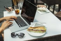 Зайняті жінки використовують ноутбук і смартфон для роботи на обід. — стокове фото