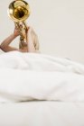 Menina tocando trompete na cama — Fotografia de Stock
