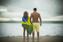 Casal jovem, mulher envolta em bandeira brasileira, Praia de Ipanema, Rio de Janeiro, Brasil — Fotografia de Stock
