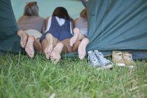 Три молодые женщины подруги ноги у входа в палатку — стоковое фото