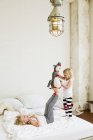 Little sisters playing with soft toy on the bed — Stock Photo