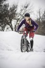 Mid adulto mulher mountain biker lutando para montar através da neve — Fotografia de Stock