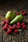 Pears and raspberries on wooden surface — Stock Photo