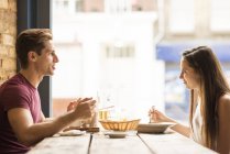 Casal jovem conversando enquanto come no restaurante — Fotografia de Stock