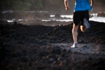 Чоловік біжить на кам'янистому пляжі — стокове фото