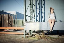 Женщина сидит на стене в промышленной зоне — стоковое фото