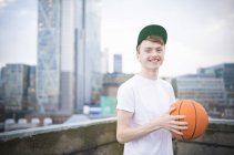 Adolescente menino segurando basquete na cidade urbana — Fotografia de Stock