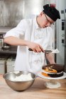 Чоловічий шеф-кухар, що глазурує торт на комерційній кухні — стокове фото