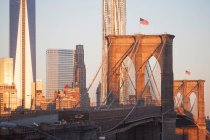 New York City bridge with flag on top and skyline at sunset — Stock Photo