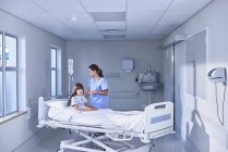 Infirmière ajustant le goutte-à-goutte intraveineuse pour la patiente au lit dans le service des enfants de l'hôpital — Photo de stock