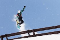 Сноубордист перепрыгивает через металлические перила — стоковое фото