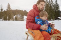 Young man and son tobogganing in snow, Elmau, Bavaria, Germany — Stock Photo