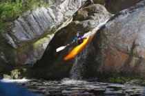 Homme adulte milieu kayak en aval de la cascade de la rivière — Photo de stock