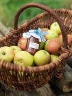 Pommes dans le panier avec pot de confiture de pommes — Photo de stock