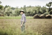 Teenage boy standing looking over his shoulder in ploughed field — Stock Photo