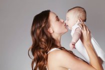 Mãe beijando bebê filha — Fotografia de Stock