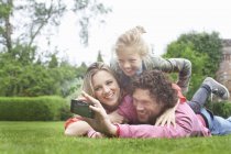 Father photographing family lying on lawn — Stock Photo