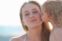 Portrait of young girl kissing older sister — Stock Photo
