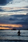 Swimmer silhouetted at dusk, Tenby, Wales, UK — Stock Photo