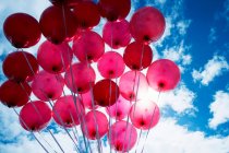 Vista ad angolo basso di palloncini rosso vivo contro il cielo blu — Foto stock