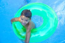 Retrato do menino no anel inflável na piscina do jardim — Fotografia de Stock