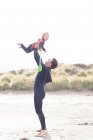 Отец поднимает сына на пляж — стоковое фото
