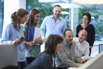Empresários masculinos e femininos reunidos em torno da mesa no escritório — Fotografia de Stock