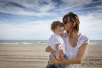 Mid adult woman kissing toddler daughter on beach, Castelldefels, Catalonia, Spain — Stock Photo