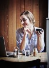 Junge Frau sitzt in Café mit Heißgetränk und benutzt Laptop-Computer — Stockfoto