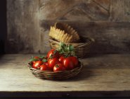 Fresh organic roma tomatoes in wicker basket — Stock Photo