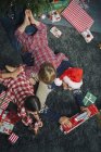 Père couché sur le plancher du salon ouvrant cadeaux de Noël avec fille et fils — Photo de stock