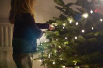 Chica joven tirando de las luces de Navidad - foto de stock