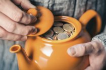 Male hands holding teapot full of coins — Stock Photo