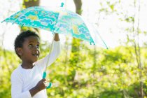 Boy carrying umbrella in forest — Stock Photo