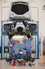 Механики, работающие на автомобиле в гараже — стоковое фото