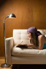 Дівчина-підліток, що пише в щоденнику, лежить на дивані — стокове фото