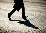 Pernas de pessoa andando sobre pedras de paralelepípedos — Fotografia de Stock