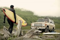 Mann trägt Surfbrett gegen Auto, Kodiak, Alaska, USA — Stockfoto