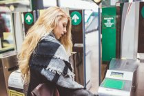 Young woman using ticket barrier in train station — Stock Photo
