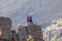 Mountain biking couple celebrating on rock formation — Stock Photo