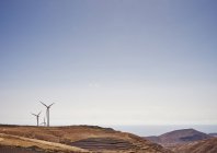 Вітрові турбіни на пагорбі з ясним блакитним небом — стокове фото