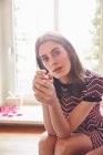 Portrait of young woman sitting on kitchen counter — Stock Photo